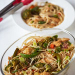 Chicken Stir Fry with Noodles in an oblong glass dish with plated stir fry with noodles in the background