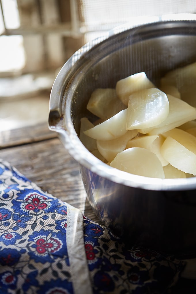 Boiled turnip slices (for turnip curry) in a small saucepan with steam rising from them.